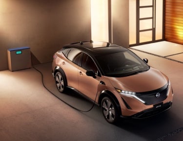 Nissan ARIYA plugged-in and charging outside a home | Benton Nissan of Hoover in Hoover AL